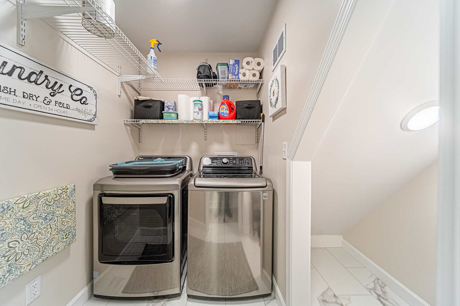 Basement laundry area with front-loading washer and dryer and new white tile flooring in Tippecanoe County remodel
