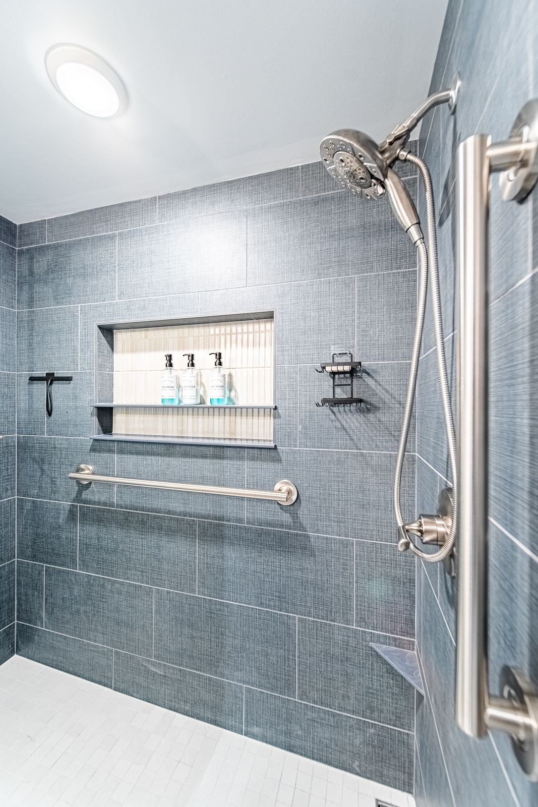 White shaker vanity with quartz-style top and modern hardware, set against marble-look floor tile in a remodeled Lafayette bathroom.