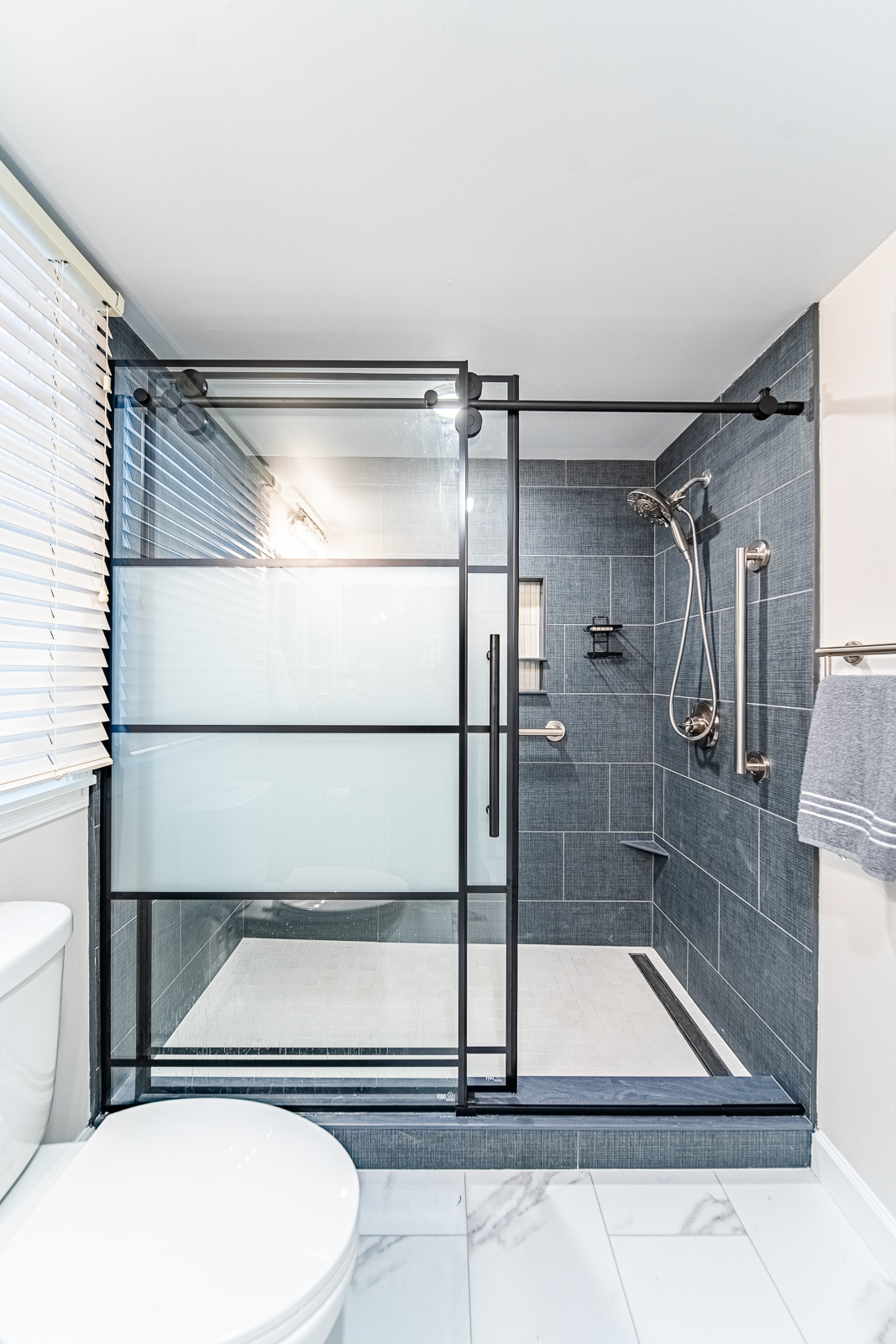 Wide-angle view of modern basement bathroom with shower, toilet, and vanity in Tippecanoe County remodel