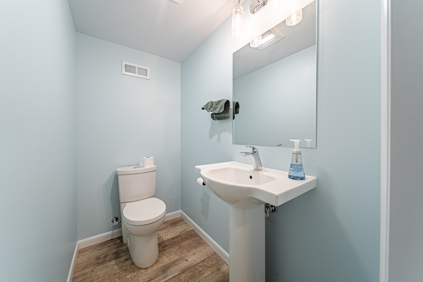 View of powder room with pedestal sink and overhead vanity lighting.