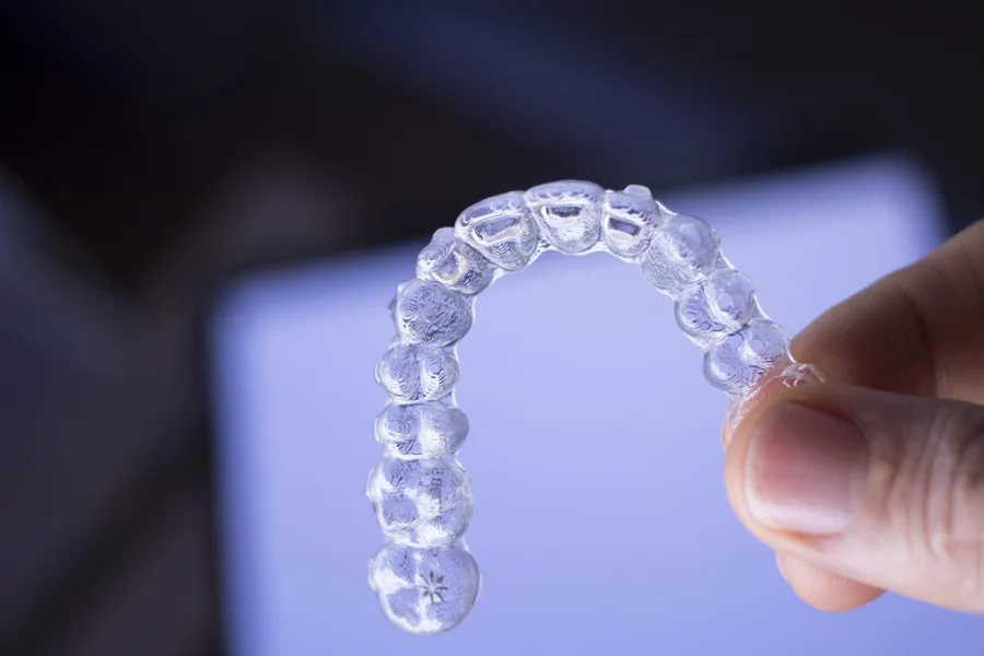 Hand holding a clear Invisalign aligner in Clearwater, FL