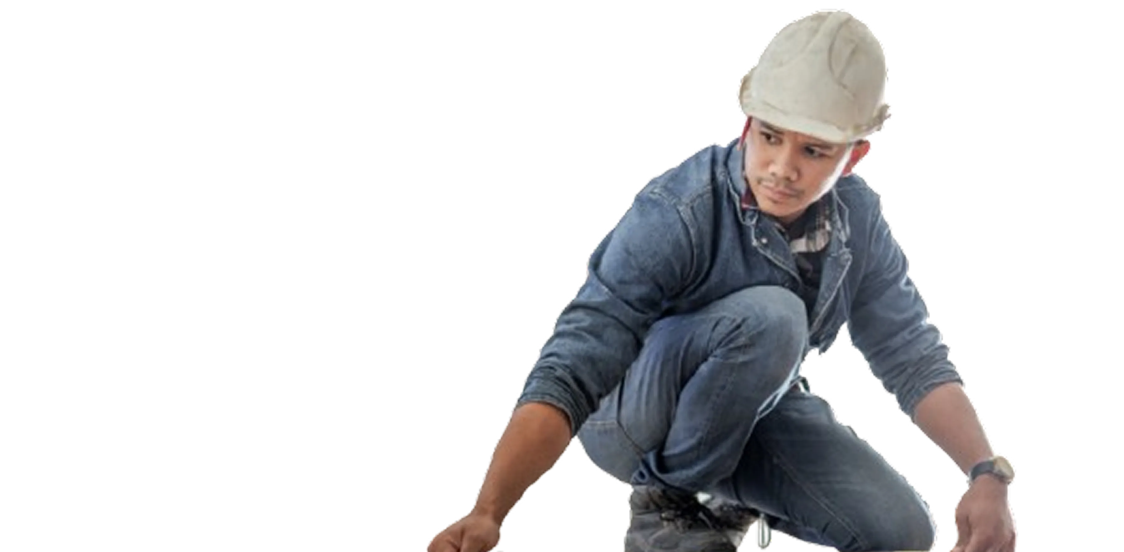 Construction worker wearing a white hard hat and denim outfit crouched and reaching forward.