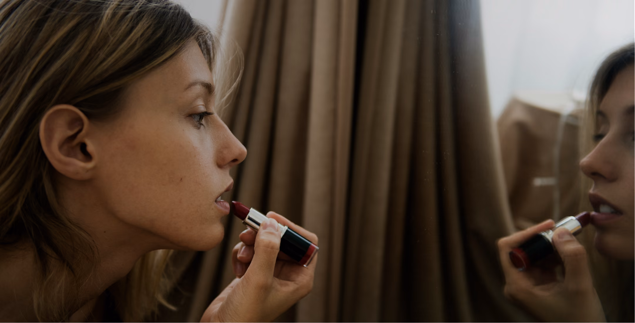 woman applying lipstick in a mirror
