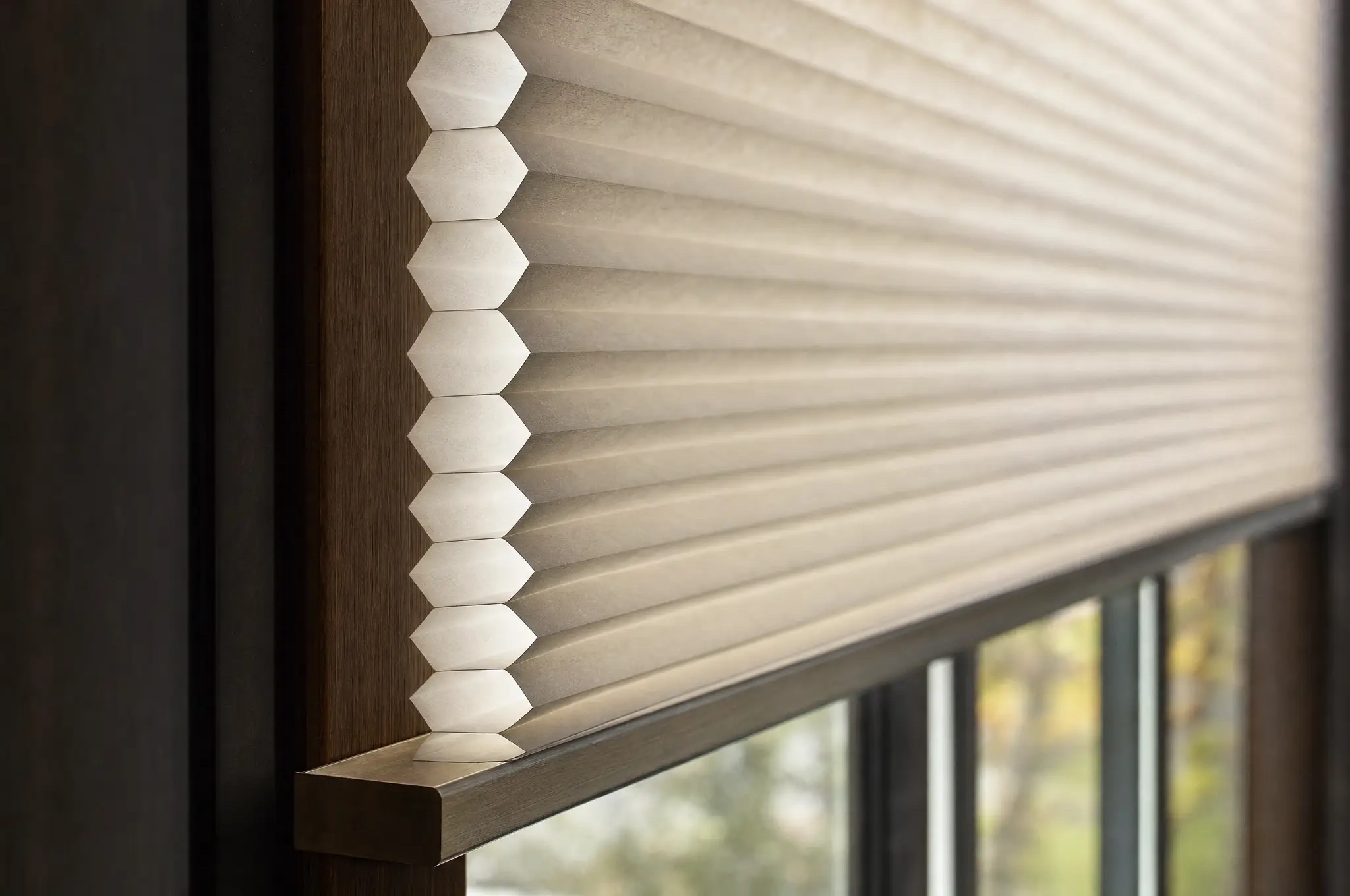 Close-up of a cream Hunter Douglas honeycomb shade in a dark wood window frame