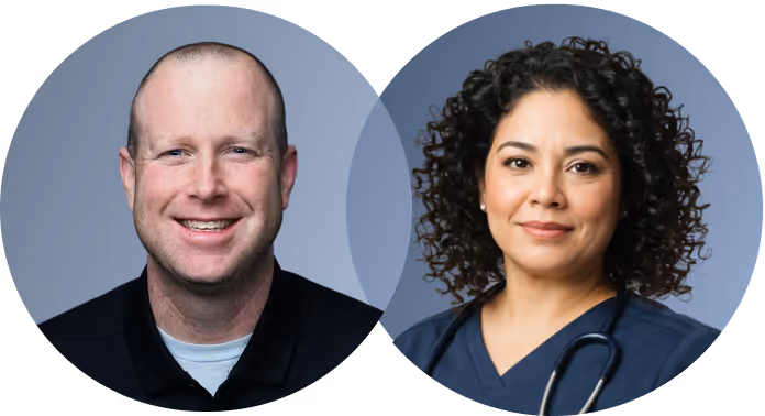 Smiling man in black shirt and woman with curly hair wearing navy scrubs and stethoscope on gray background.