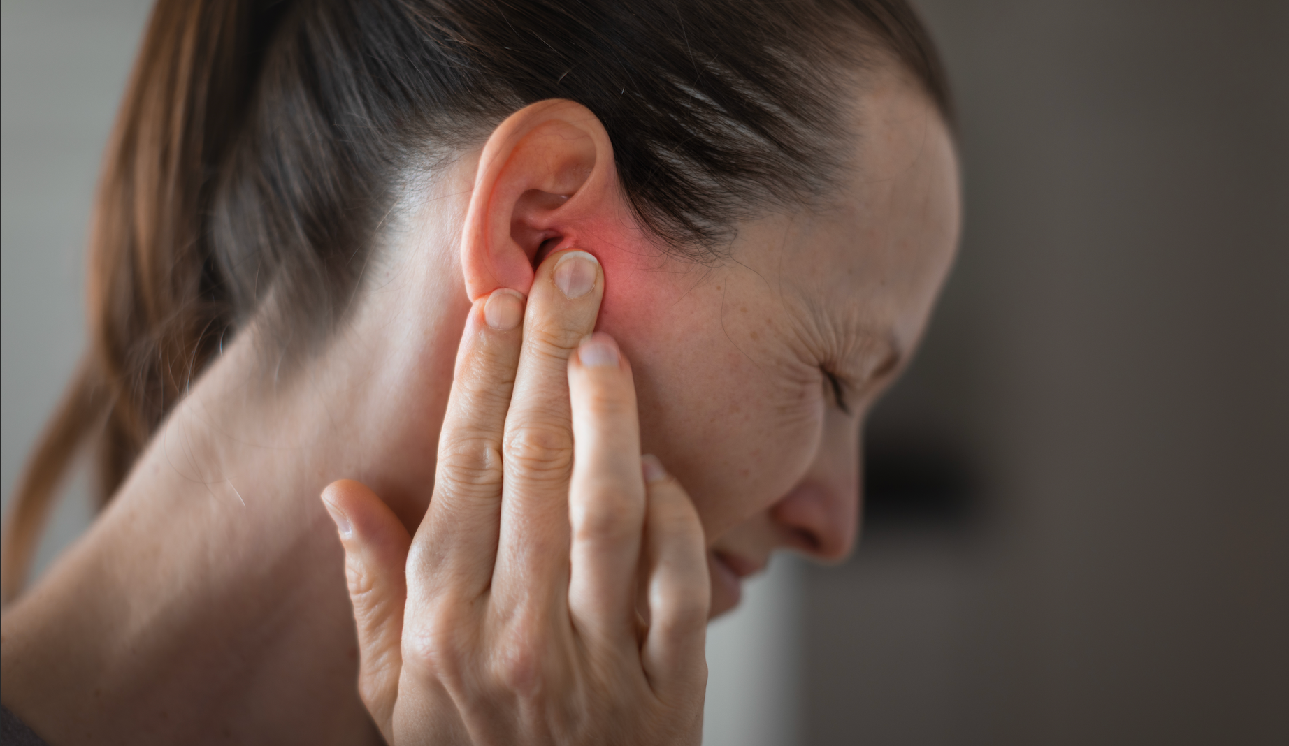 A women experiencing acute jaw pain showing TMJ symptoms