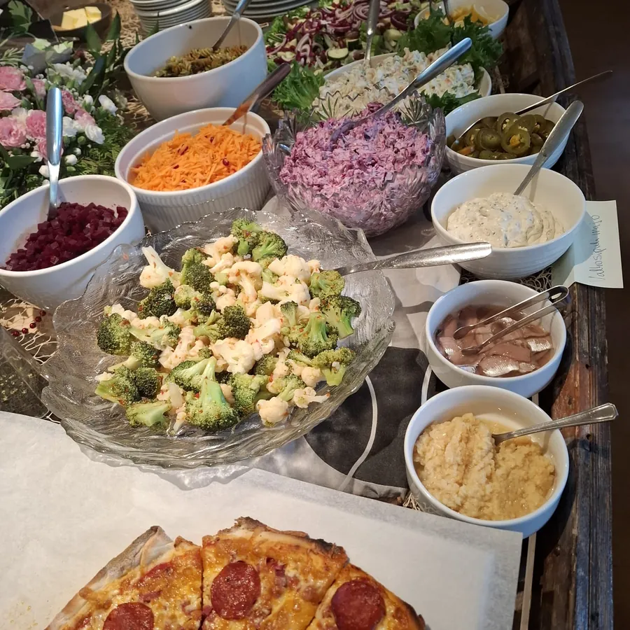 Juhlabuffet: salaatteja, kasviksia, kastikkeita ja pizzaa tarjolla