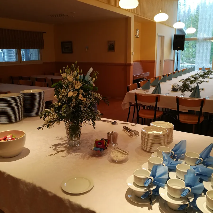 Kahvitarjoilu katettuna, taustalla pitkä pöytä isolle ryhmälle
