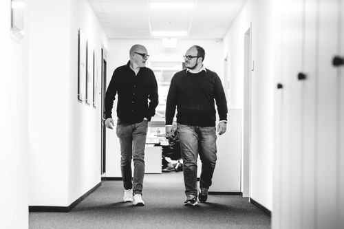 Martin Schießl und Max Weber im Büroflur laufend