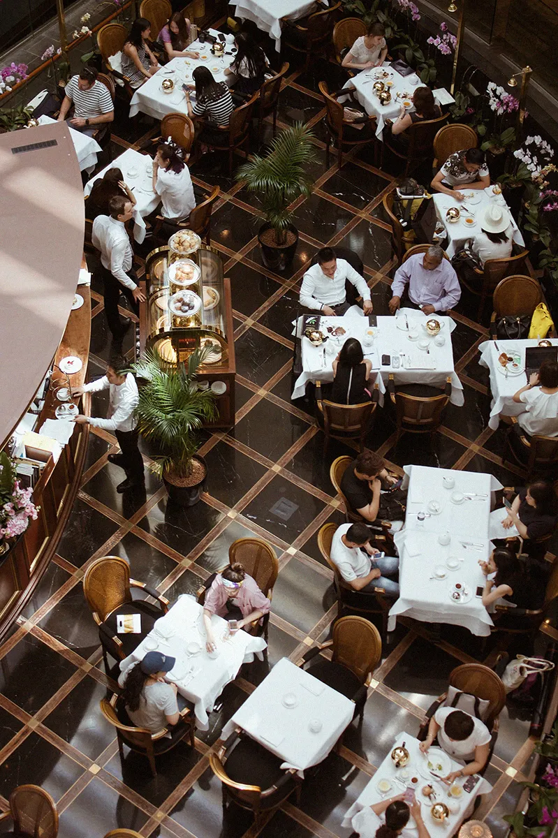Top-down image of a lively restaurant scene, with people seated at tables and the restaurant staff serving food.