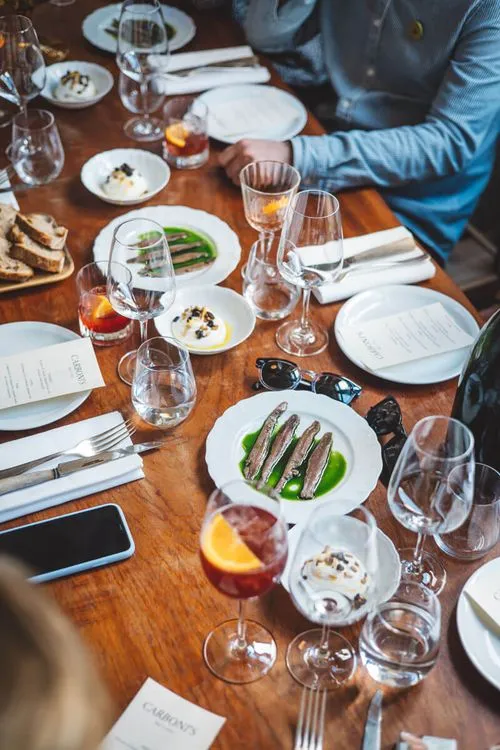 People dining together at a table set with plates, glasses, bread, and various dishes.