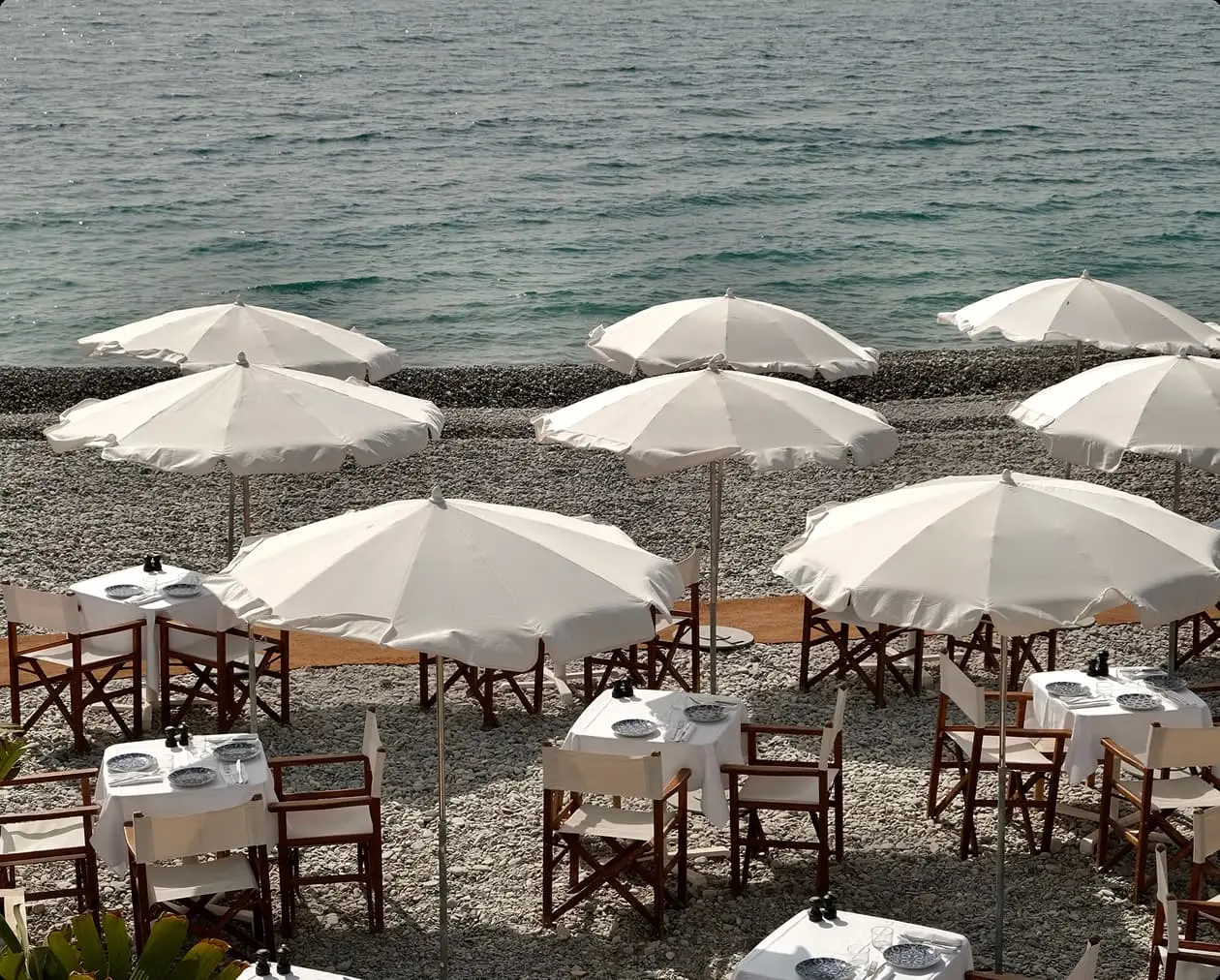 Beachfront dining area with several tables and chairs.