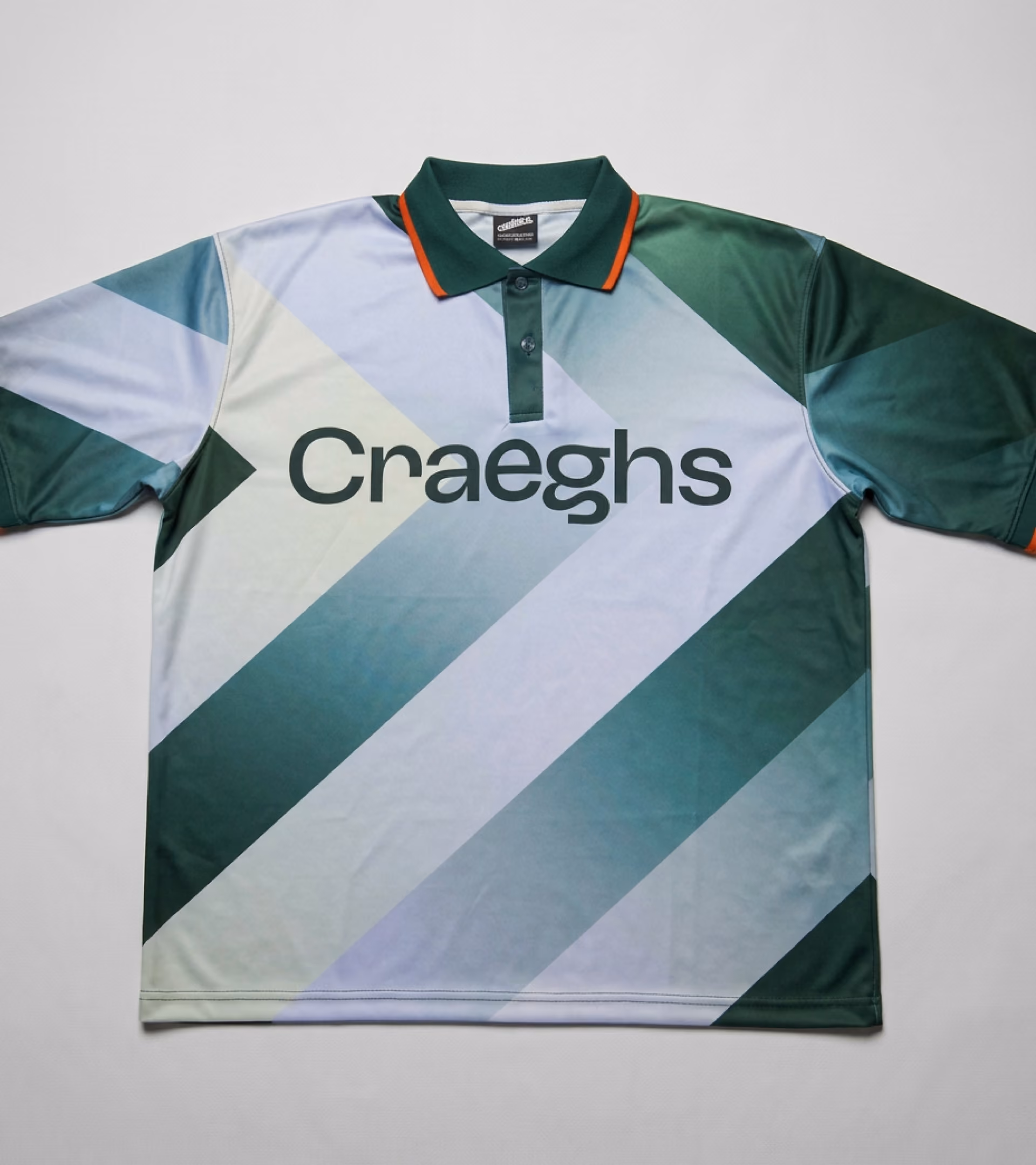 Groen-wit sportshirt ontwerp als corporate merchandise met diagonale strepen en het woord 'Craeghs' centraal op de voorkant, met een groene kraag en oranje biezen.