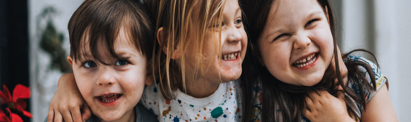 Three smiling young children hugging