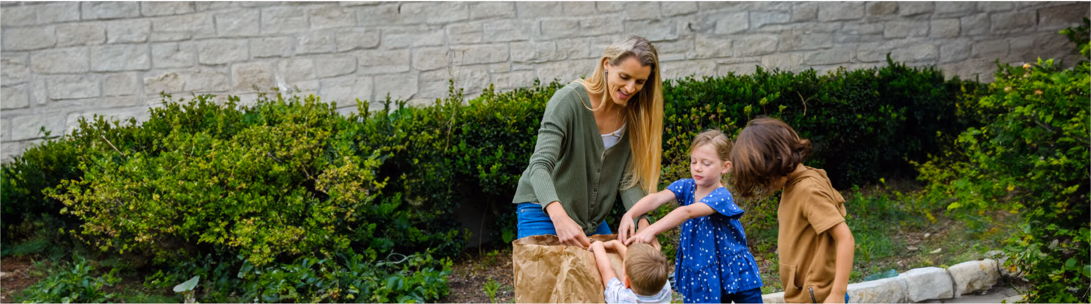 Mother and two children gathering yard waste in a backyard