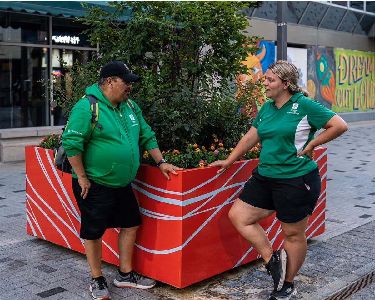 Two City of London employees standing around a colourful planter printed with wayfinding pattern on exterior.
