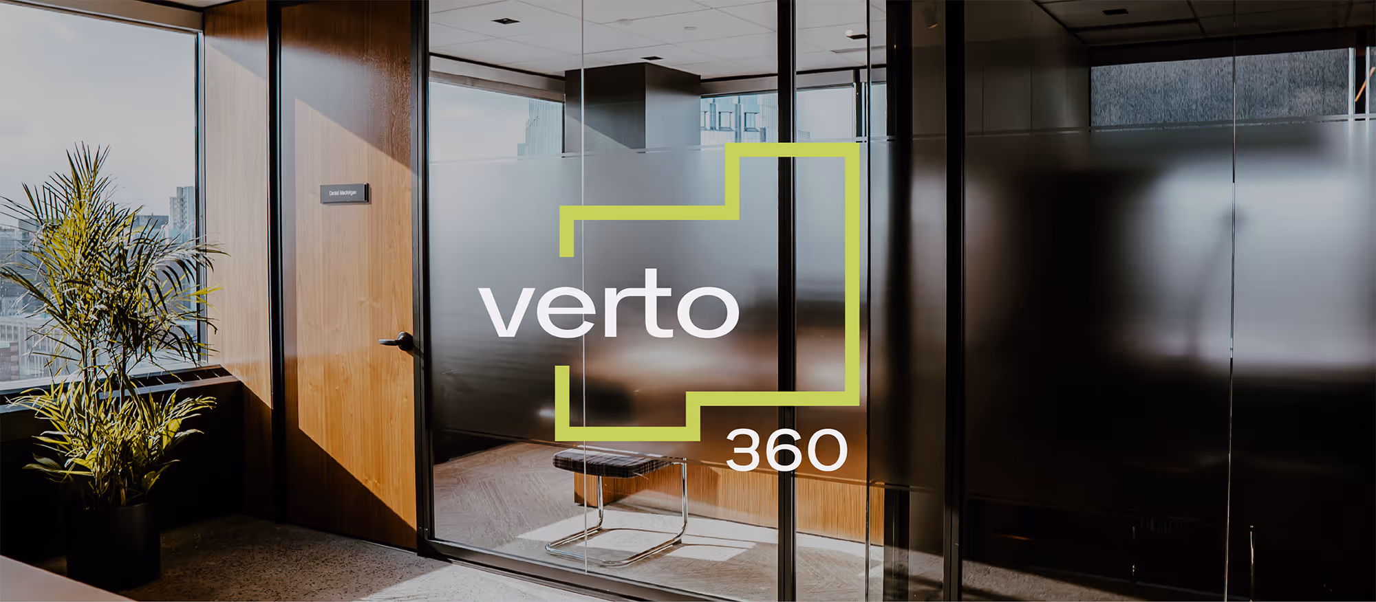 Office entrance with glass door =, a wooden wall, and a potted plant by a window. White and green Verto360 logo is overlaid on top.