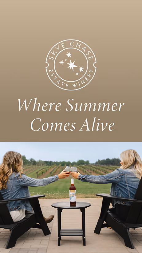 Digital Ad: Two women seated outdoors in black chairs clink wine glasses over a small round table with a bottle of wine, facing a vineyard under a cloudy sky, above text reads 'Skye Chase Estate Winery Where Summer Comes Alive'.