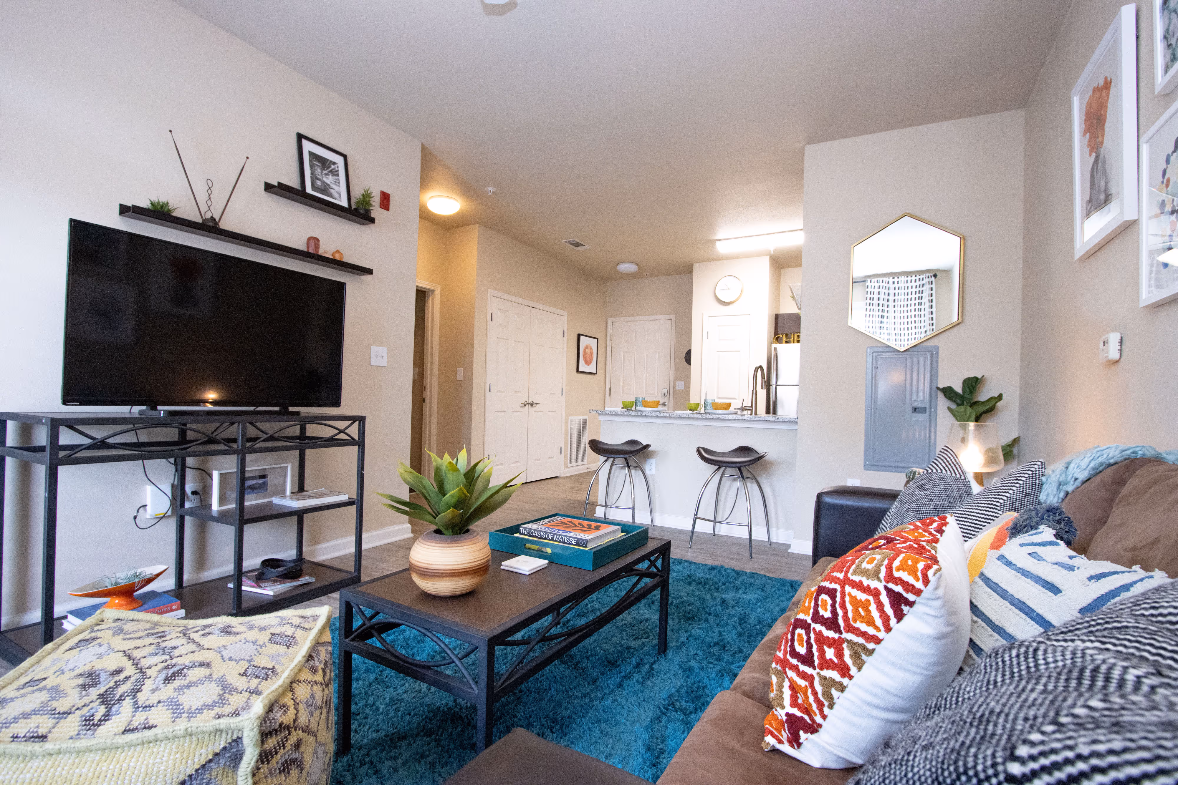 Open-concept apartment living room with a TV, coffee table, and a view into the kitchen bar and dining area at Rev Oxford in Oxford, MS.