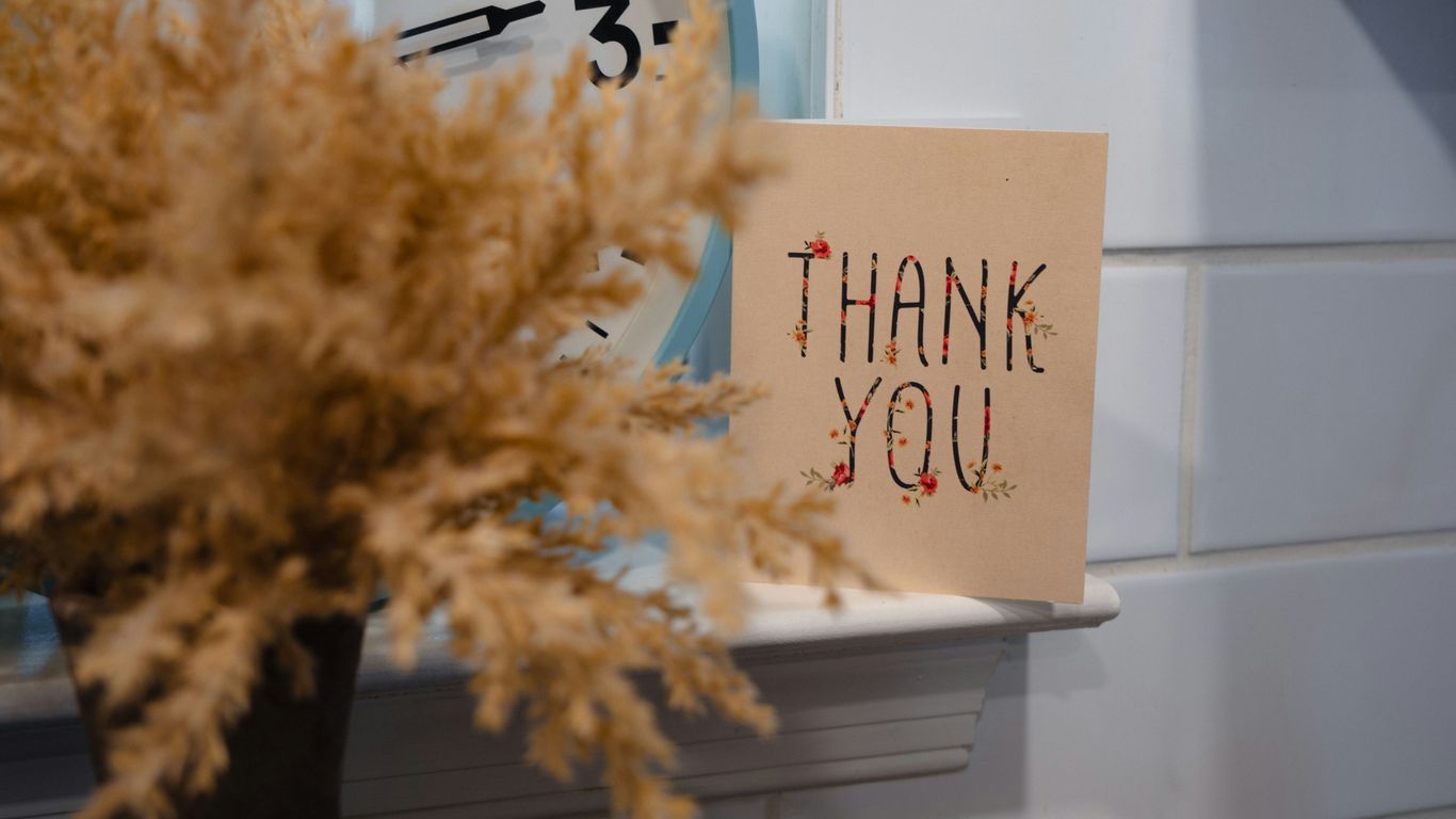 a thank you note sitting next to a clock