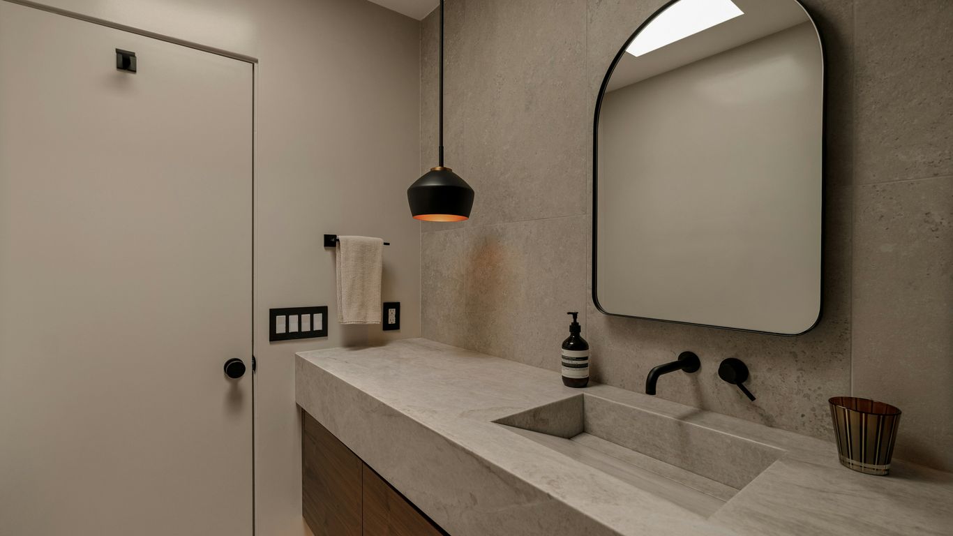 Modern bathroom with concrete sink and black faucet.