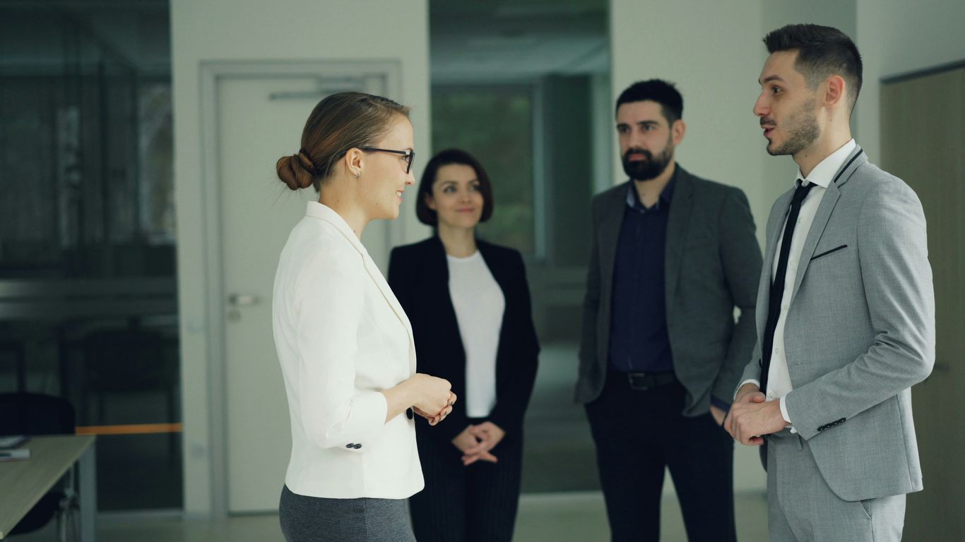 Business professionals conversing in a modern office hallway.