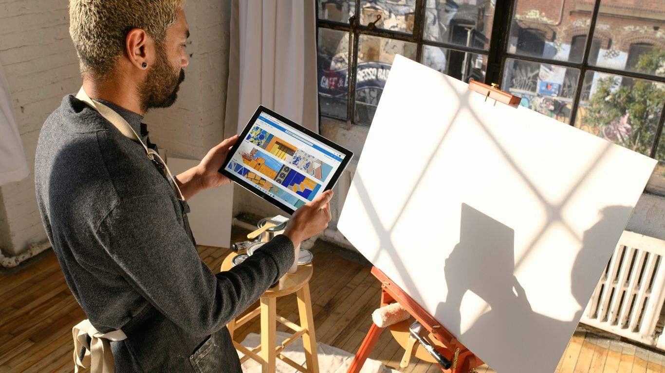 a man standing in front of a easel holding a tablet
