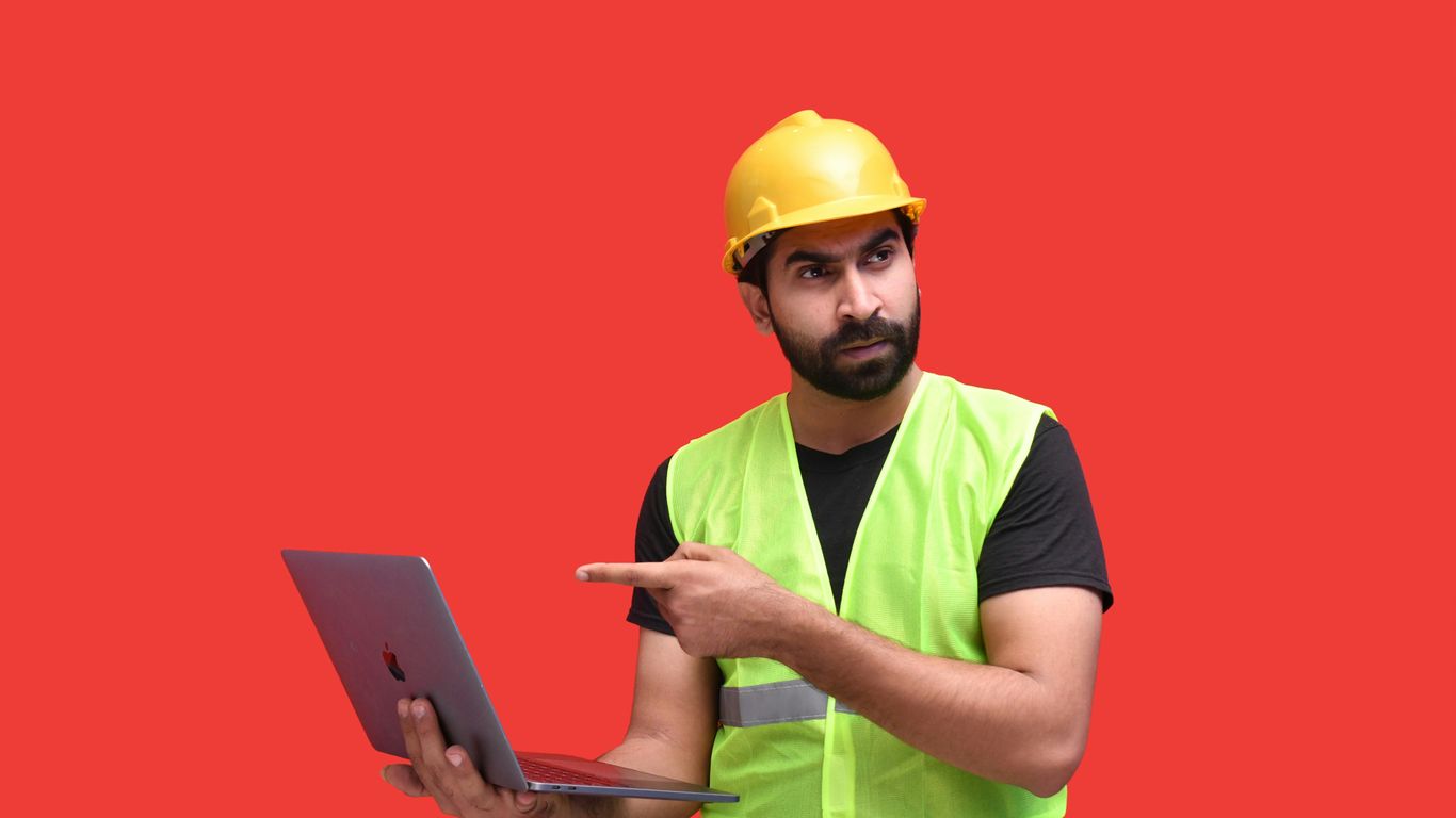 a man wearing a hard hat and holding a laptop