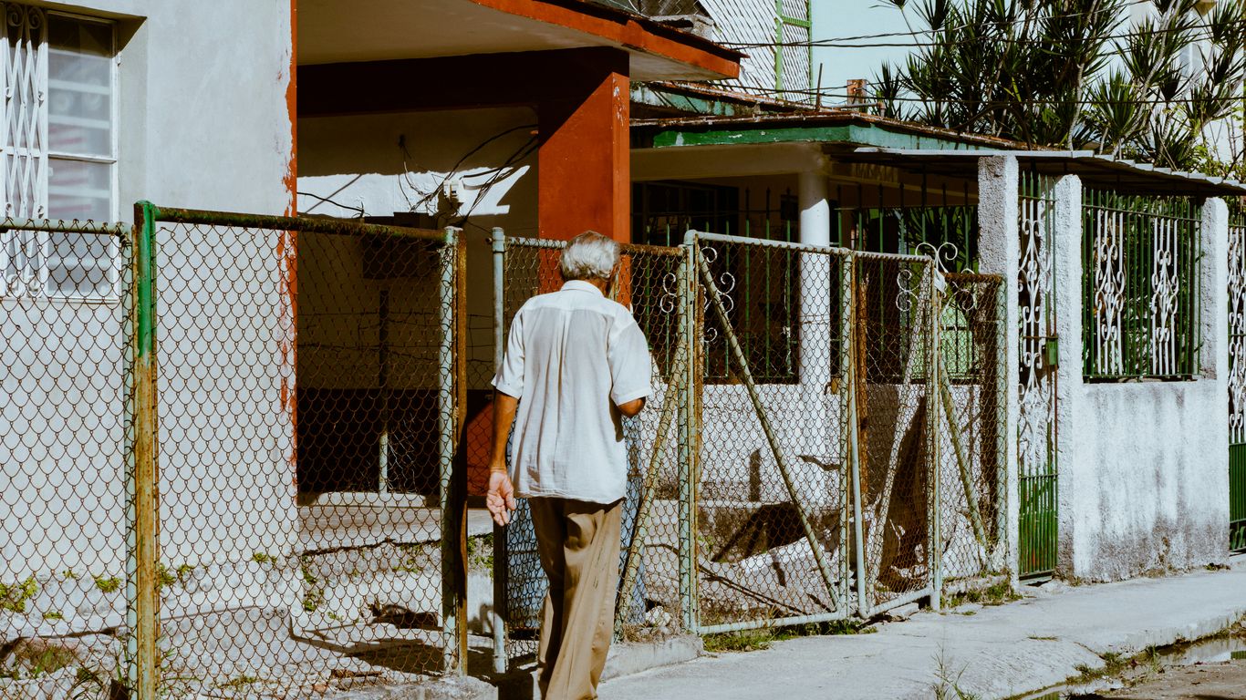 a man walking down a street next to a fence