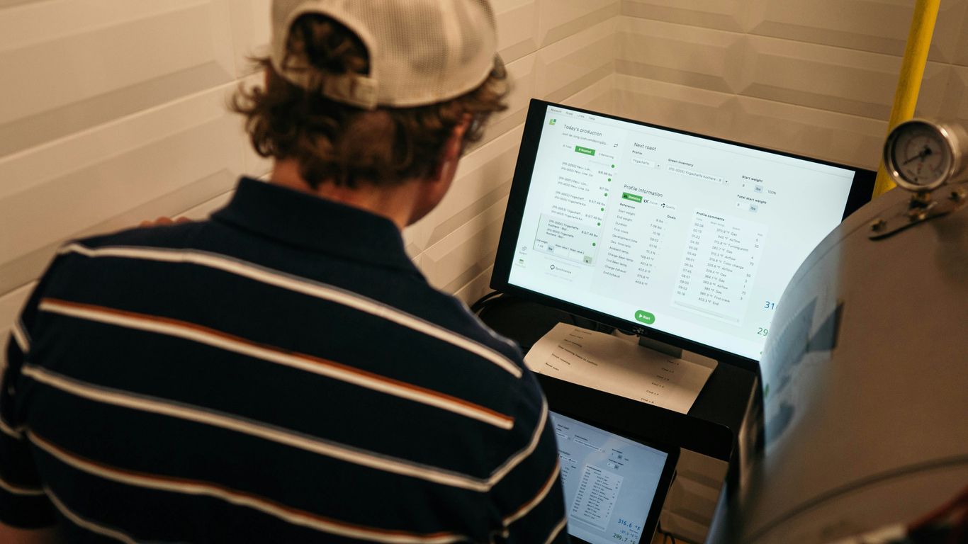 man in white and black striped polo shirt in front of monitor