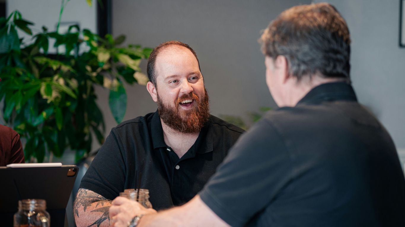 two men sitting at a table talking to each other