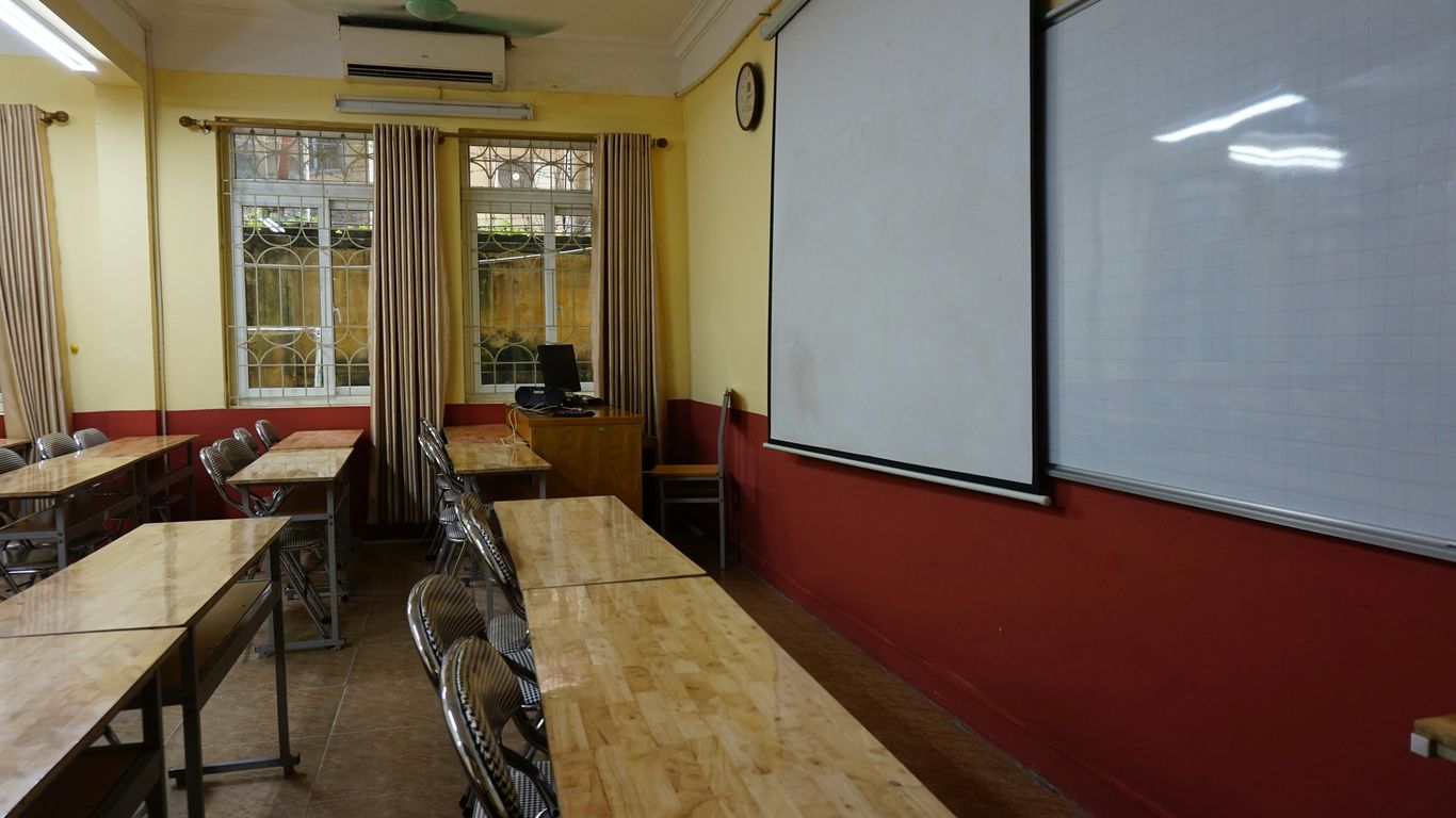 A classroom with tables and chairs and a whiteboard