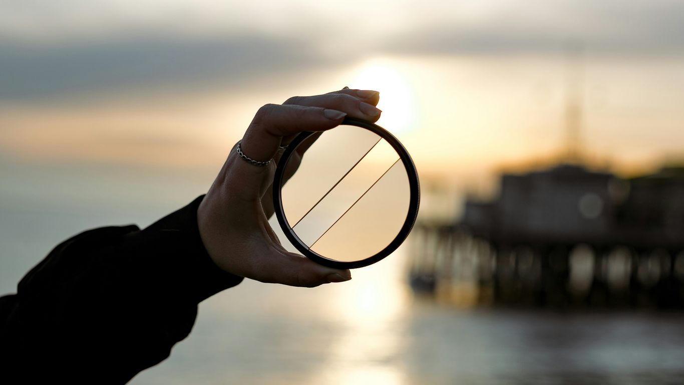 a person holding a circular object in front of a body of water