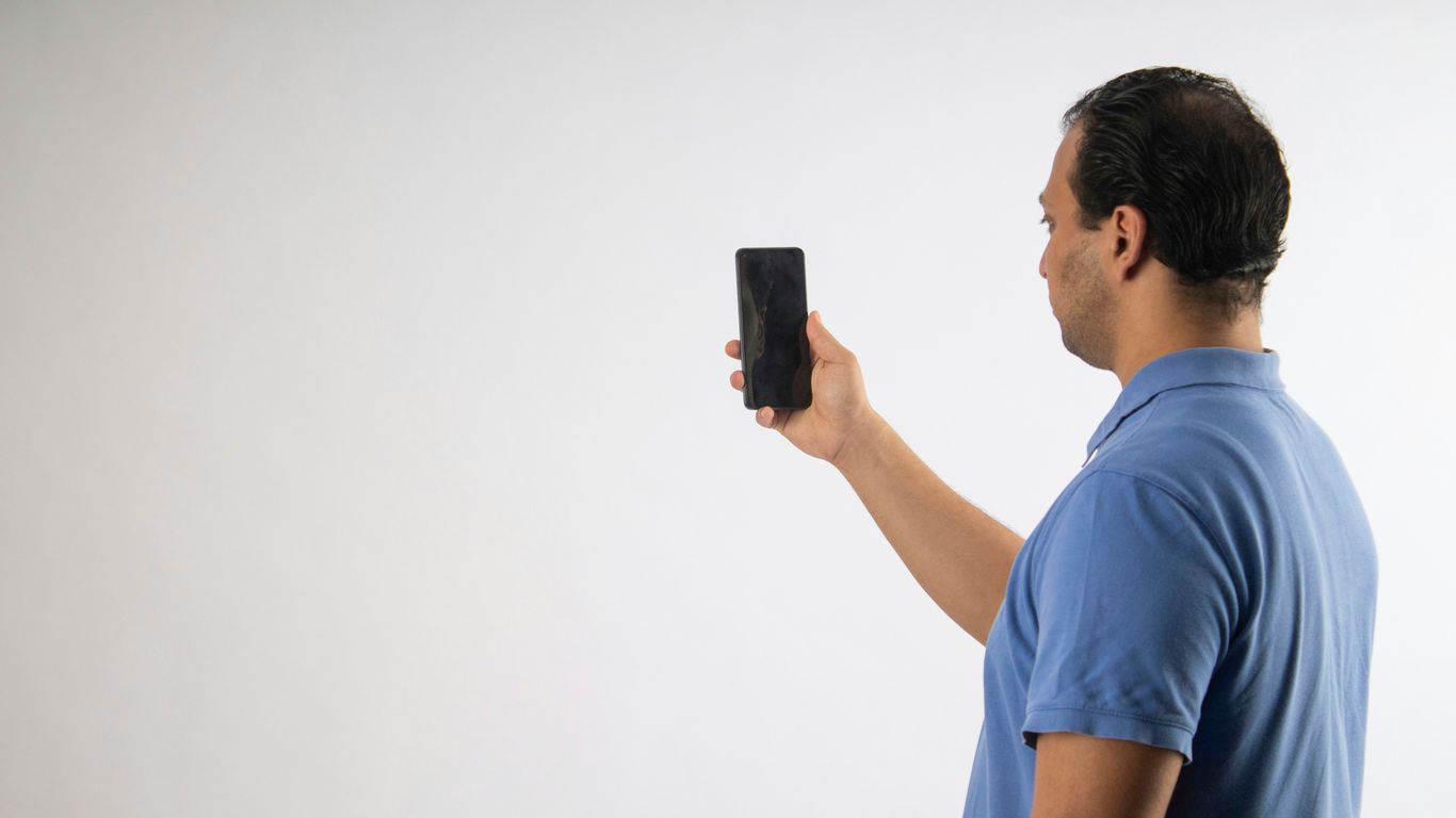 A man is holding up a cellphone.