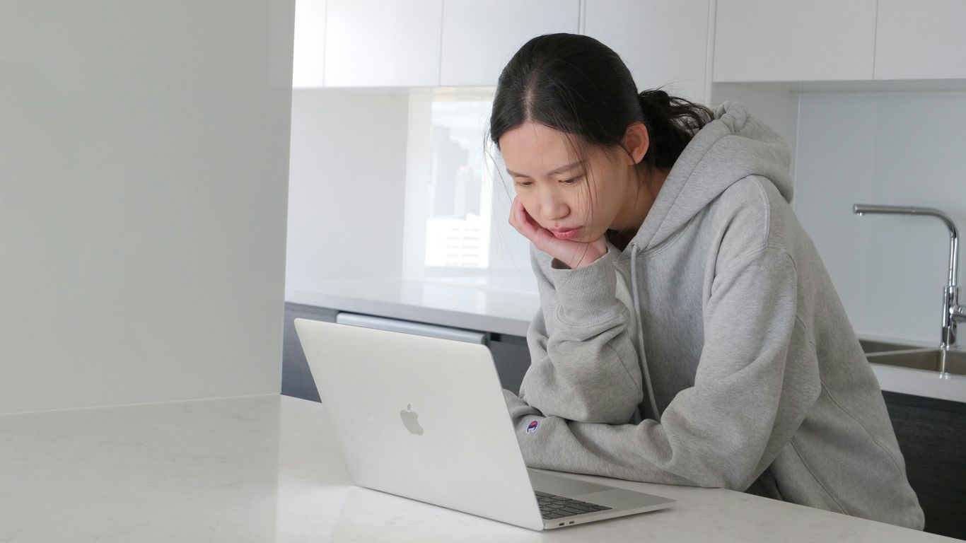 man in gray hoodie sitting beside white table