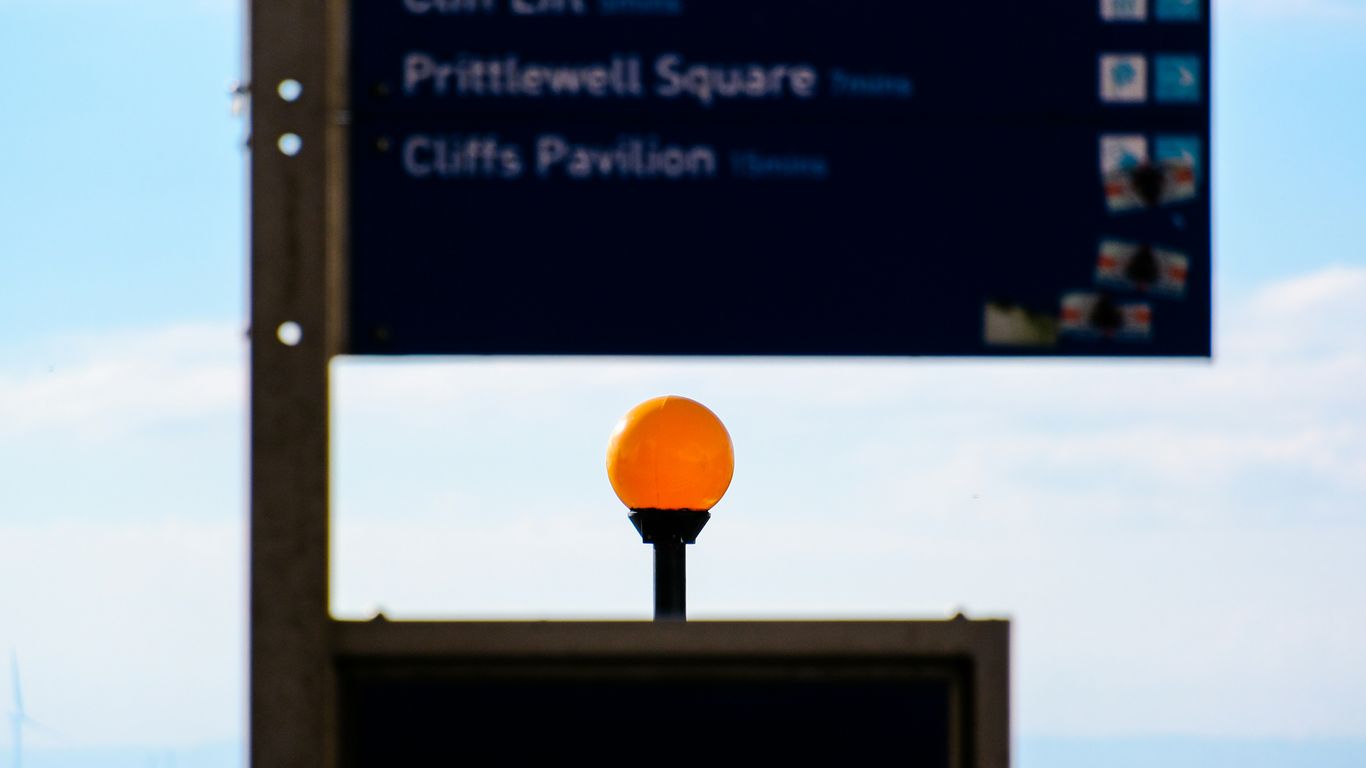 A street sign with an orange ball on top of it