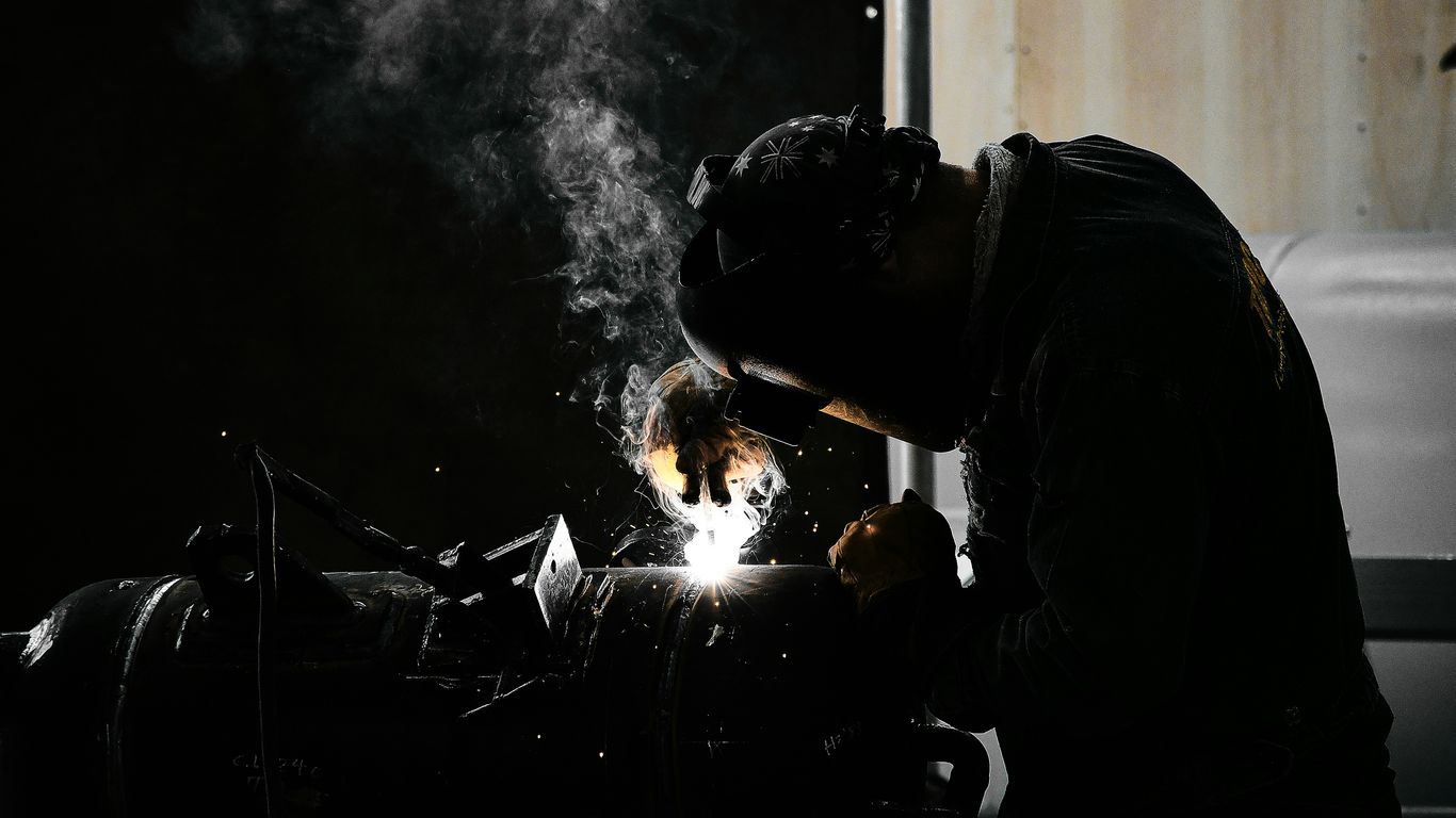 A man welding a piece of metal in a dark room