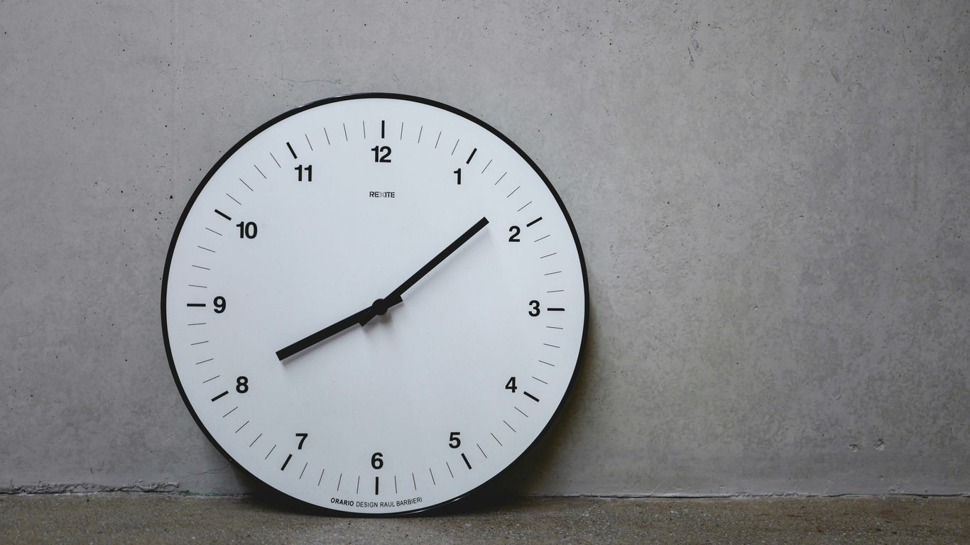 a white clock on a wall with a black second hand
