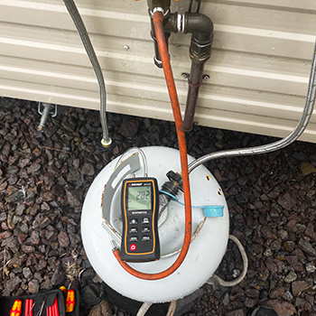 Gas meter testing device placed upon LPG bottle during routine gas servicing