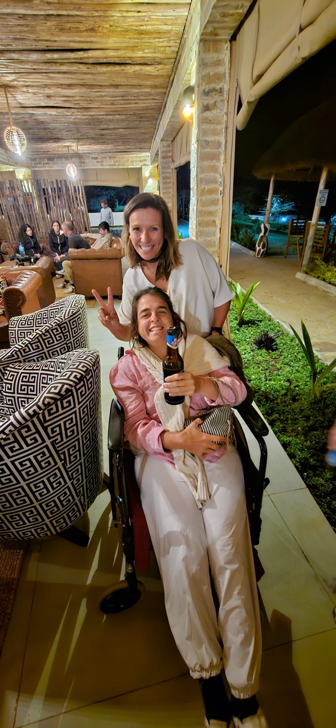 Dos mujeres sonríen en el salón de un lodge de safari por la noche