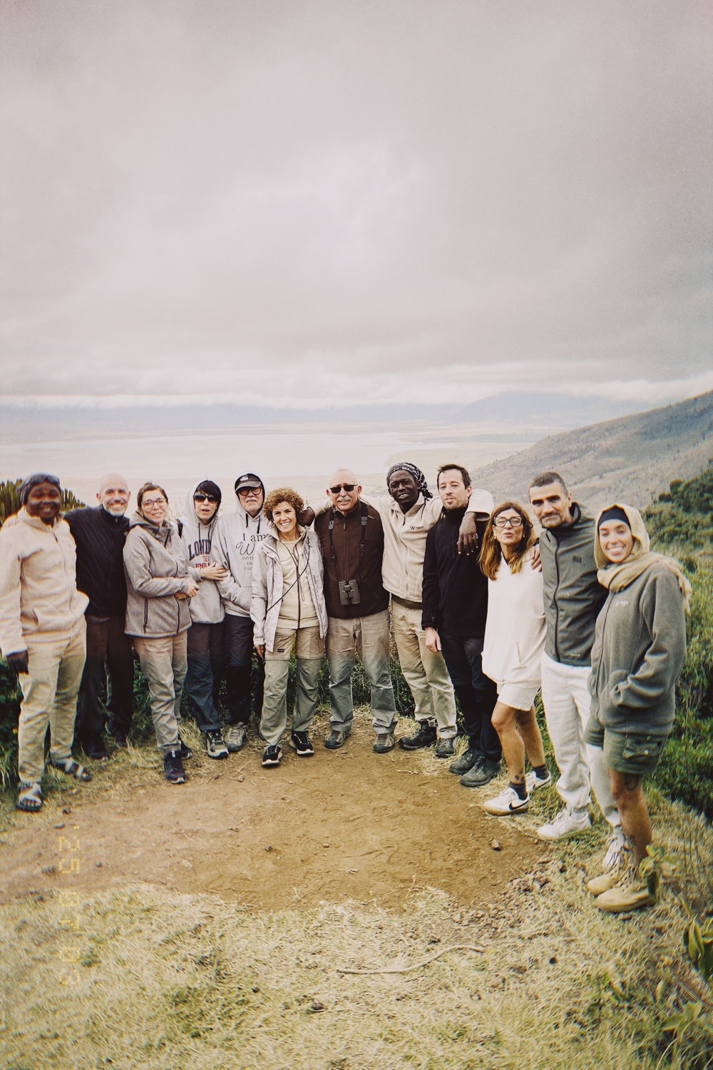 Group of smiling tourists posing on a highland viewpoint with vast crater landscape behind