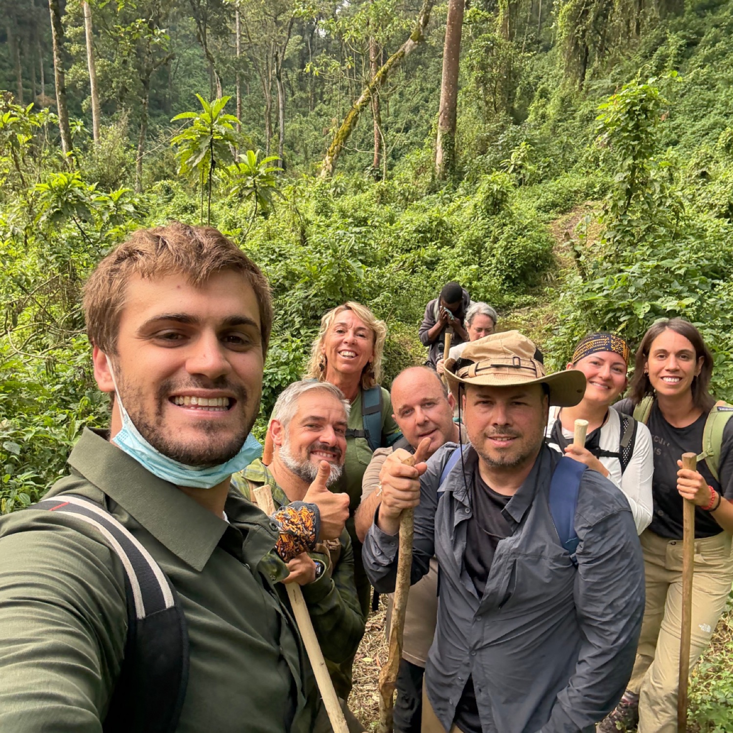 Grup de turistes somrients amb bastons de senderisme en un sender de selva tropical densa