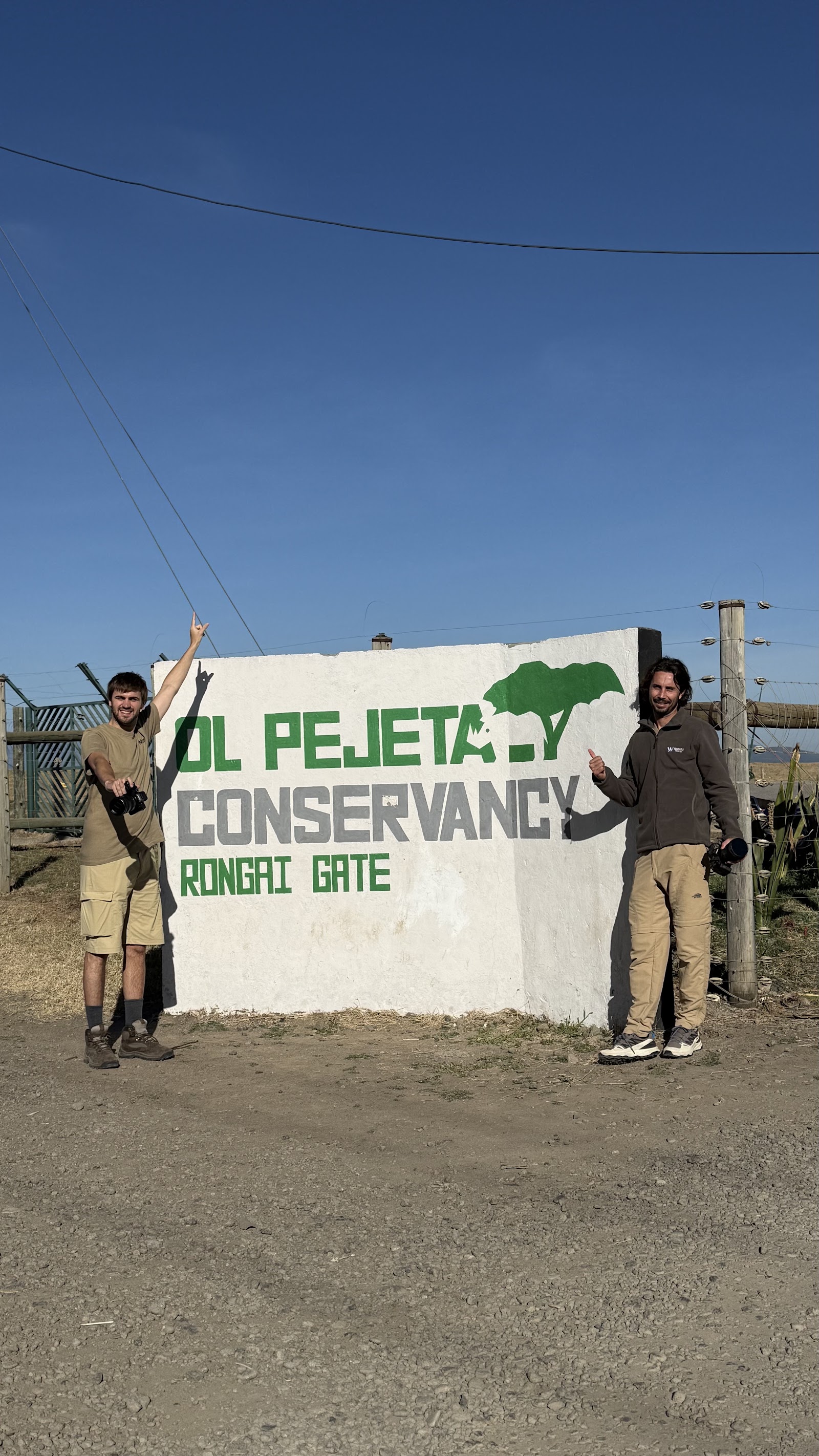 Dos viatgers posen contents davant del rètol d'Ol Pejeta Conservancy a Kenya