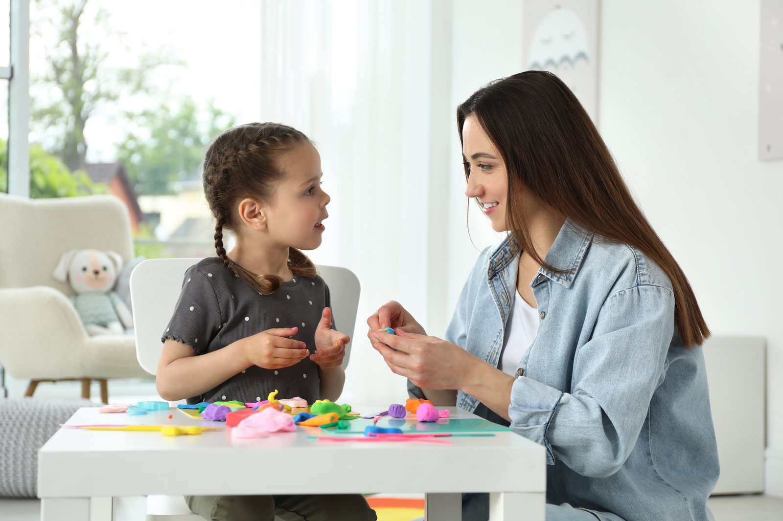 A child shaping playdough with a therapist during a play-based ABA session