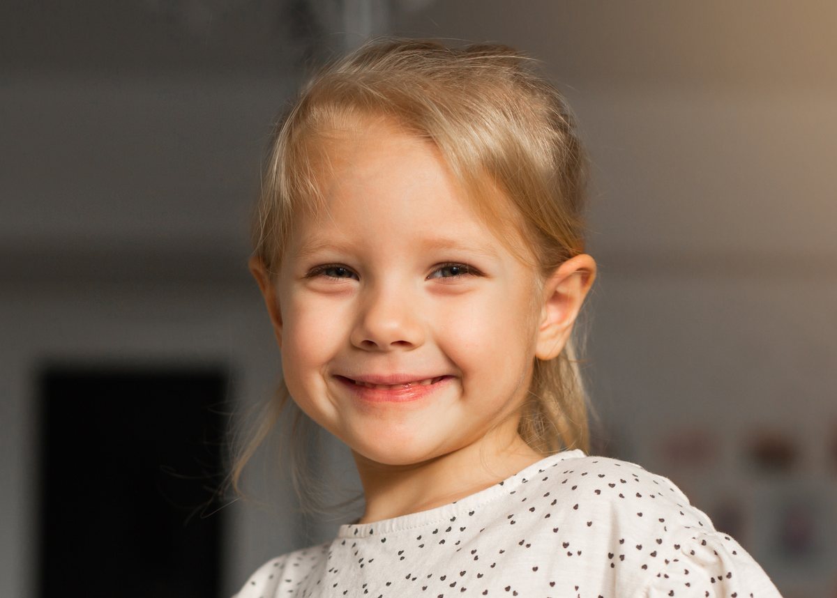 A young child smiling at home, early-intervention age range