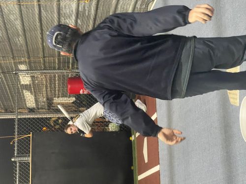 Coach tossing a ball to a batter