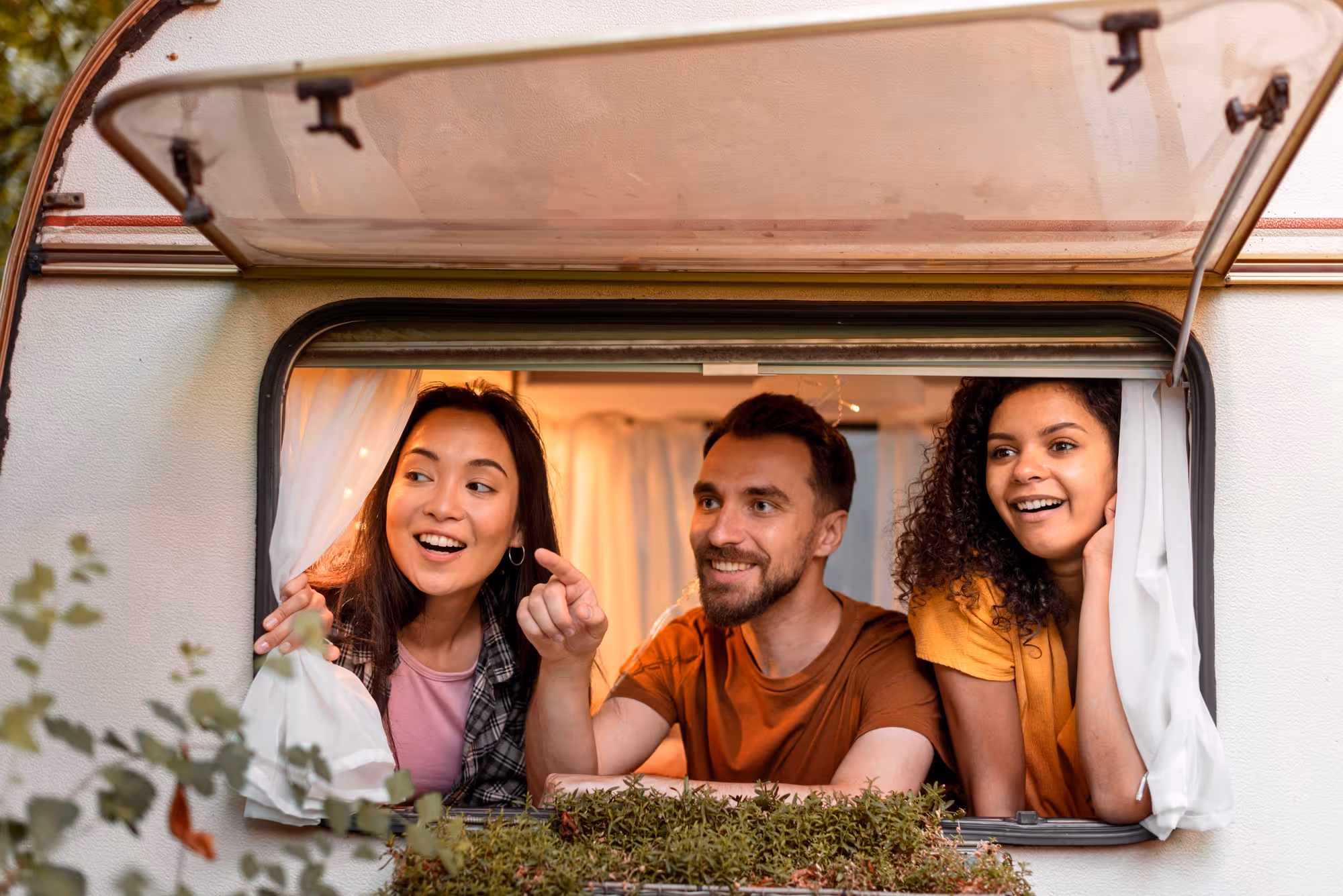 3 people looking from inside the window of a campervan