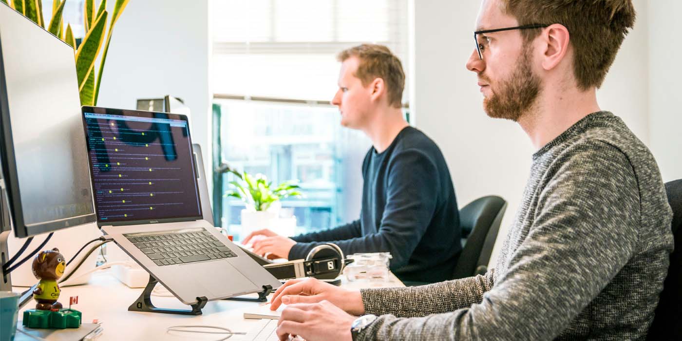 An image of two men at their desks in an office environment for the Maximise Your Efficiency with WhatsApp Business on Desktop blog post by ClientWindow