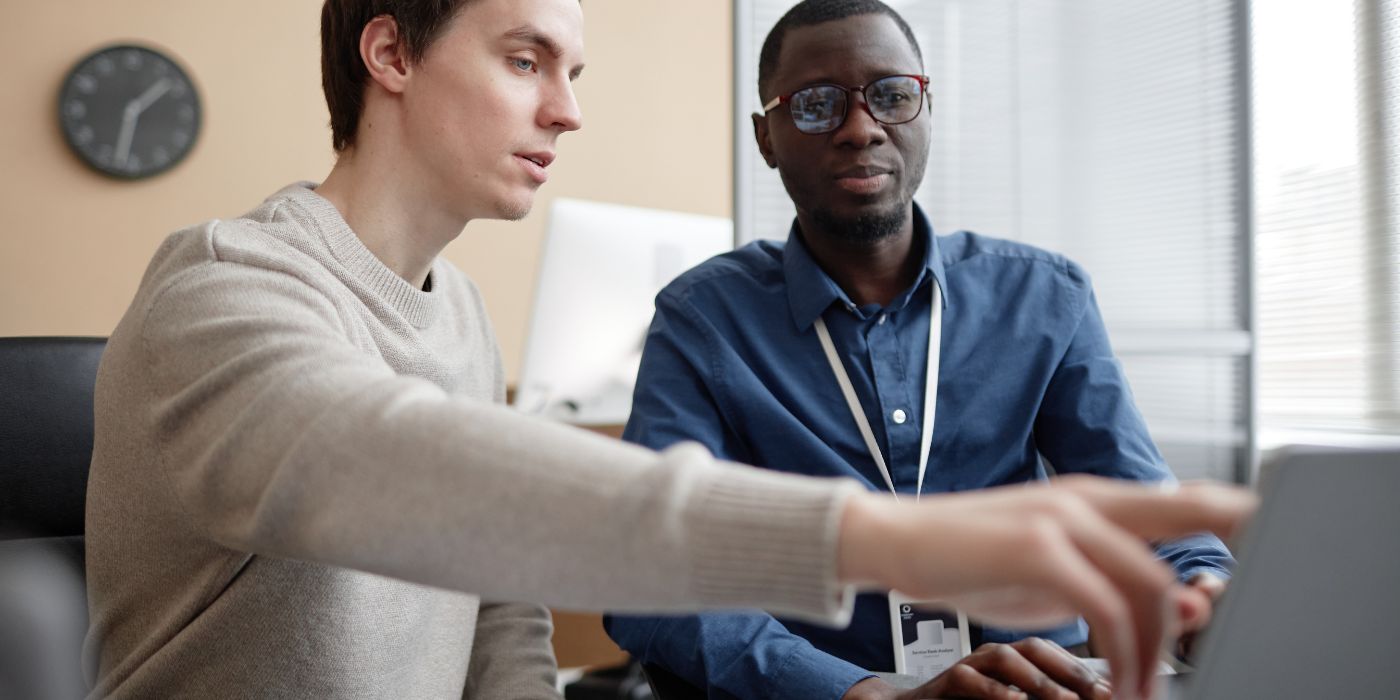 Two professionals at desk pointing to device