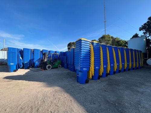 Dozens of blue garbage and recycling bins stacked on top of one another.